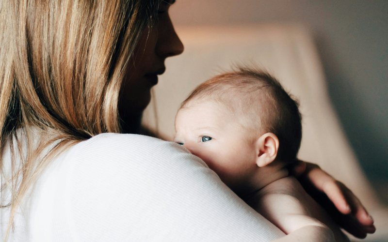 A mother holding her newborn against her shoulder