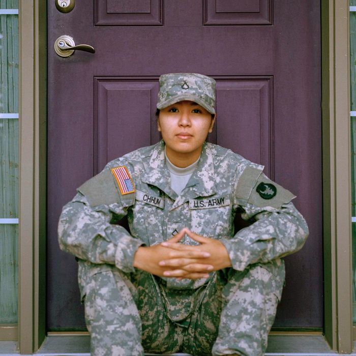 A soldier sitting on the front step of a house.