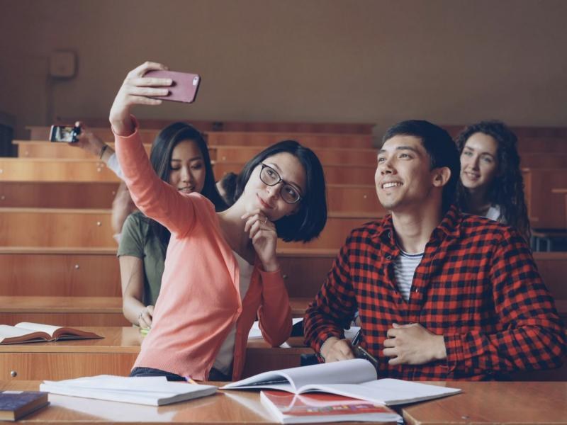 Two students taking a selfie at a table