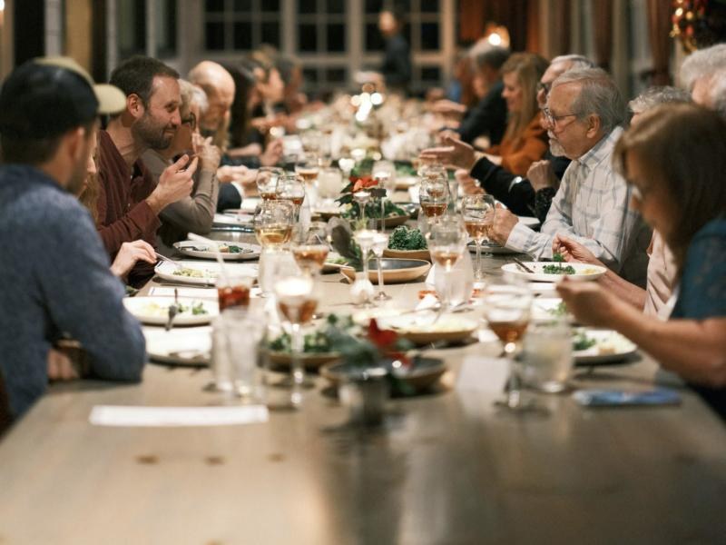 A long family dinner table full of people talking