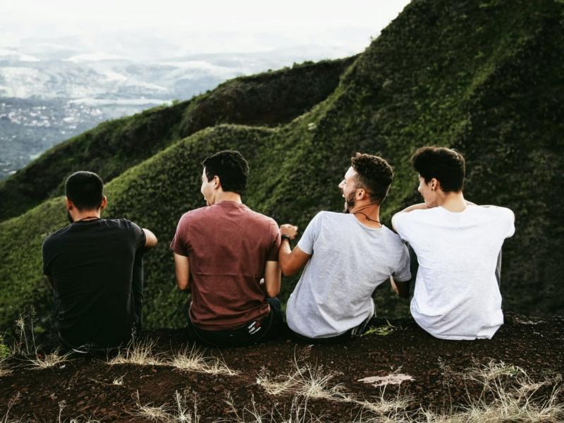 Four friends sitting together on a green hillside